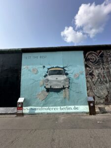 Mural “Trabant atravessando o muro” de Birgit Kinder, mostrando o carro símbolo da Alemanha Oriental quebrando o Muro de Berlim.