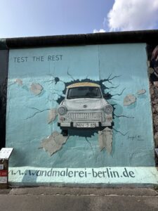 Mural “Trabant atravessando o muro” de Birgit Kinder, mostrando o carro símbolo da Alemanha Oriental quebrando o Muro de Berlim.